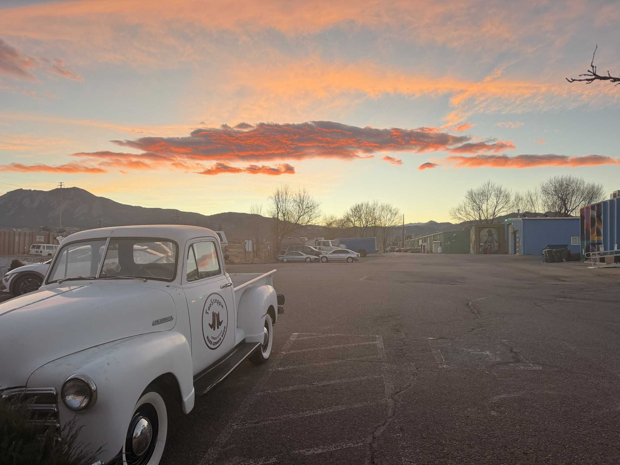Vintage white truck in a parking lot with a colorful sunset sky